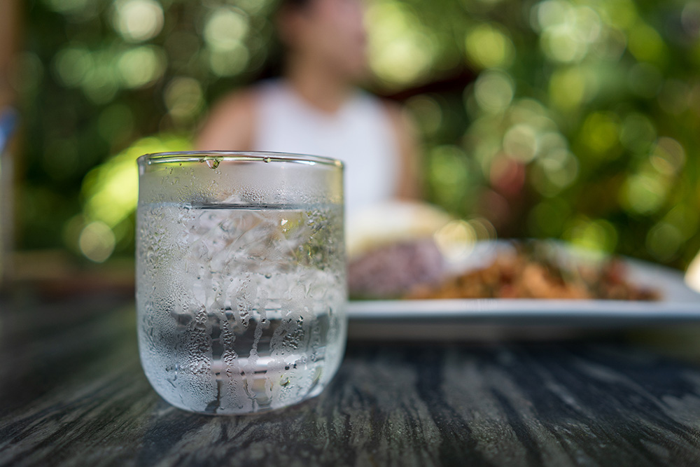 An ice cold glass of water sitting on a picnic table, showing the satisfaction of upgrading the water within your san antonio home.