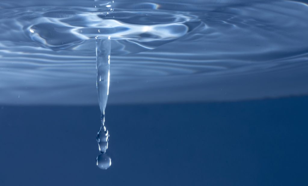 An image of a droplet of water falling into a larger body of water